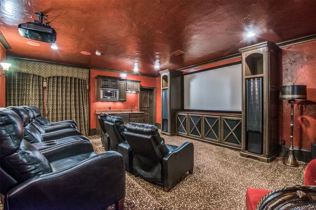 The lower level media room has media chairs, a 3D projector with glasses, Martin Logan speakers, and a wet bar with microwave and drink fridge. All are included. | Image 29