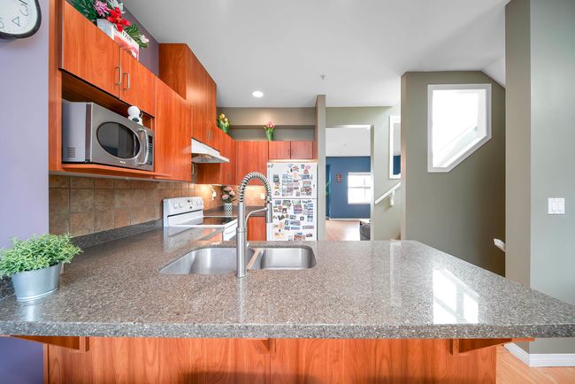 Kitchen with a peninsula, a sink, white appliances, brown cabinets, and under cabinet range hood | Image 17