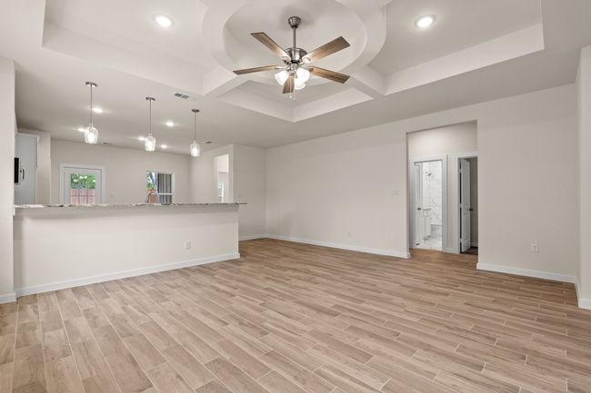 Unfurnished living room featuring coffered ceiling, light wood-style flooring, baseboards, ceiling fan, and recessed lighting | Image 7