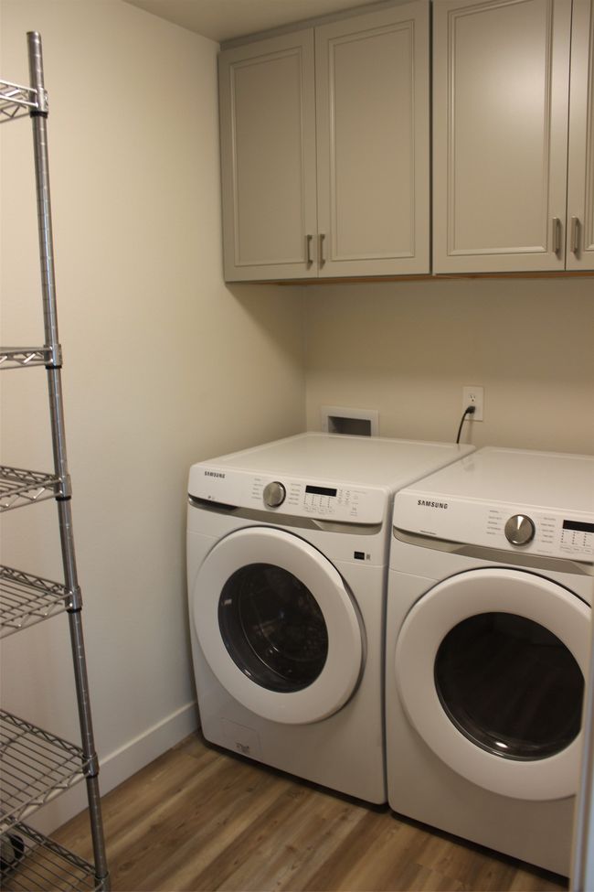 Washroom with separate washer and dryer, light wood-type flooring, and cabinet space | Image 8