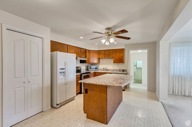 Kitchen with under cabinet range hood, light floors, a sink, appliances with stainless steel finishes, and ceiling fan | Image 7