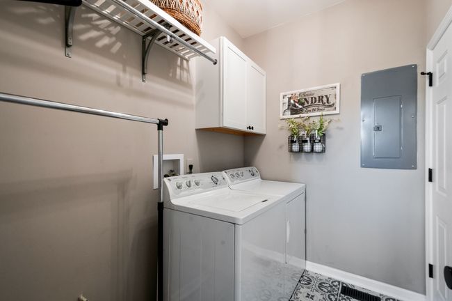 The main level laundry room is conveniently located near the primary suite and the door you see to the right is to the garage. The laundry room has a custom tiled floor and a great storage system. There is also a closet next to the garage door. | Image 29
