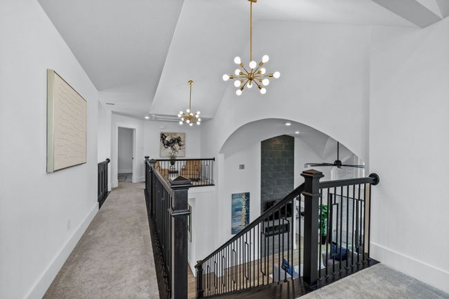 Hallway featuring a notable chandelier, carpet floors, and high vaulted ceiling | Image 29