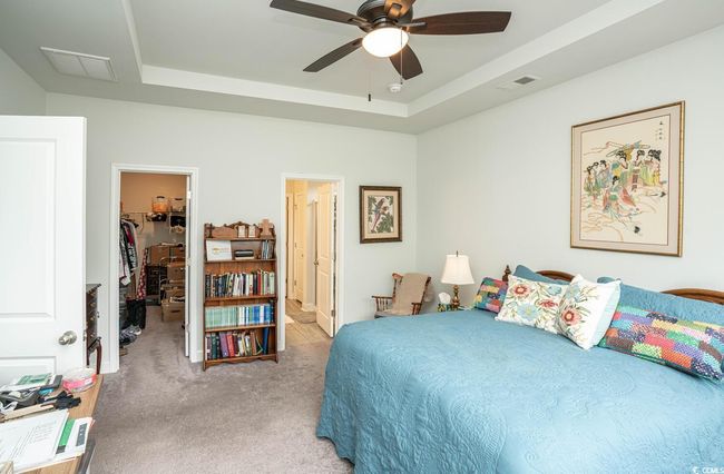 Bedroom featuring a spacious closet, light colored carpet, a tray ceiling, and ceiling fan | Image 30