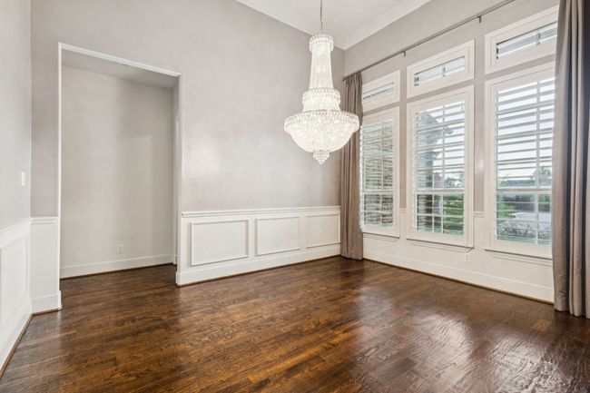 Unfurnished dining area with ornamental molding, a chandelier, wood finished floors, and a decorative wall | Image 6