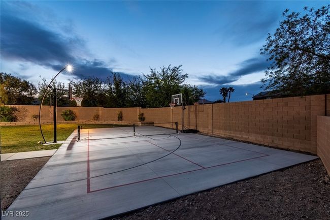 View of basketball court featuring a fenced backyard and basketball hoop | Image 48