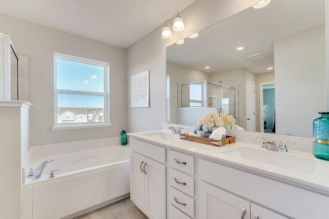 The primary suite bathroom boasts a separate shower and large soaking tub with dual sink vanity! Photo of model home, color and options will vary. | Image 16