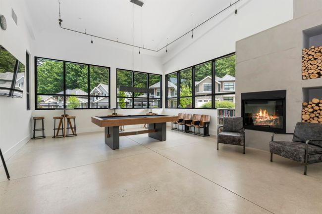 Rec room featuring billiards, finished concrete flooring, baseboards, a towering ceiling, and a glass covered fireplace | Image 32