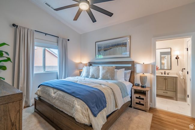 Bedroom featuring ceiling fan, connected bathroom, lofted ceiling, light hardwood / wood-style flooring, and sink | Image 34