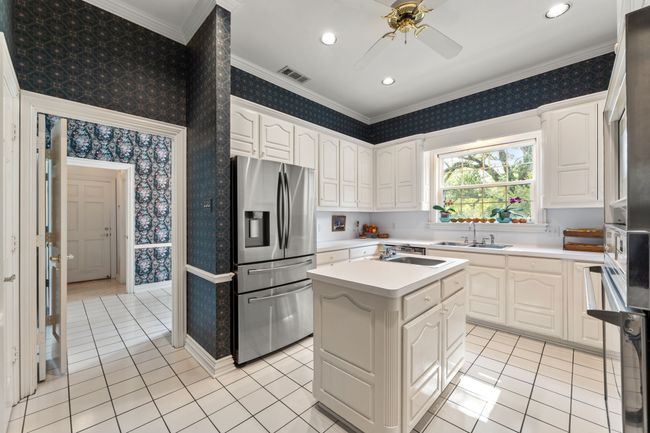 Kitchen featuring stainless steel fridge with ice dispenser, a sink, a ceiling fan, island and 2 sinks | Image 14