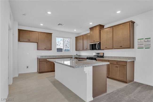 Kitchen with an island with sink, stainless steel appliances, brown cabinets, a sink, and visible vents | Image 8