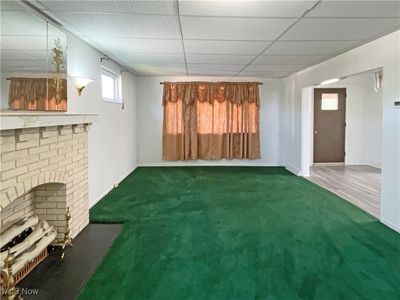 Unfurnished living room featuring dark carpet, a paneled ceiling, and a fireplace | Image 3