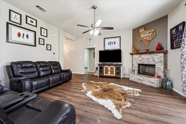 Spacious living area with tall ceilings, a cozy wood-burning fireplace, and large windows showcasing a beautiful backyard view. | Image 5
