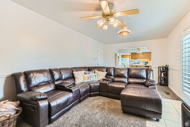 Living room featuring a ceiling fan, arched walkways, light tile patterned floors, and light carpet | Image 9
