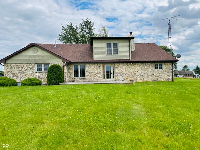 rear view of property featuring stone siding, a yard, a chimney, and roof with shingles | Image 29