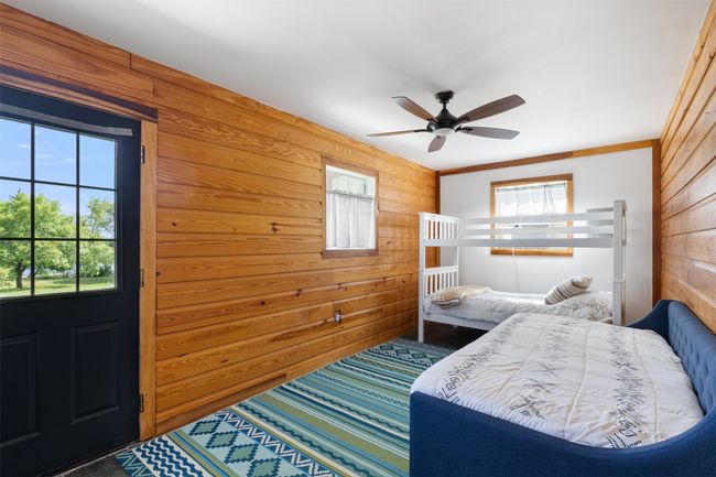Bedroom featuring wooden walls, multiple windows, and a ceiling fan | Image 31