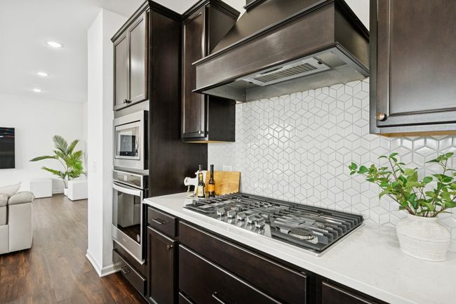 Enjoy the beauty of stainless steel appliances and a gas cooktop. | Image 11