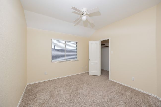 Bedroom 4 with vaulted ceiling, light colored carpet, a walk in closet, and a ceiling fan | Image 32