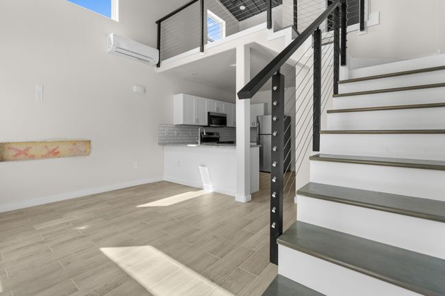 Stairs featuring a wall mounted AC, a towering ceiling, and wood finished floors | Image 13