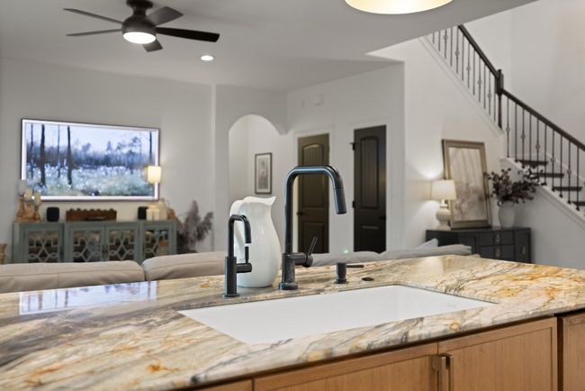 Kitchen featuring light stone countertops, a sink, arched walkways, a ceiling fan, and recessed lighting | Image 21