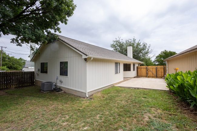 Back of property with central air condition unit, a patio, a chimney, and a shingled roof | Image 32