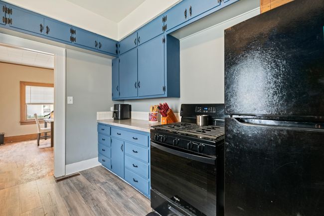 Kitchen featuring blue cabinets, black appliances, wood finished floors, and baseboards | Image 31