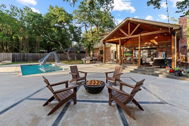 View of swimming pool with a water slide, a fenced backyard, a patio, and an outdoor living space with a fire pit | Image 33