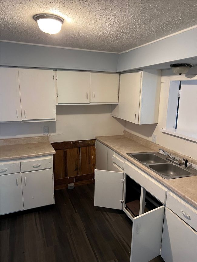 Kitchen with light countertops, white cabinets, dark wood-style floors, and a sink | Image 7