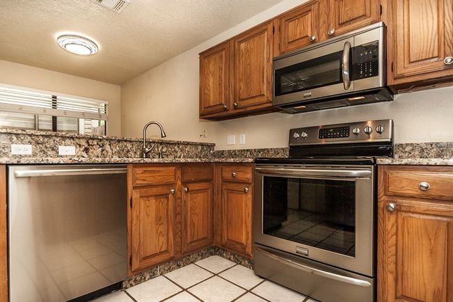 Kitchen with appliances with stainless steel finishes, brown cabinets, and stone counters | Image 8