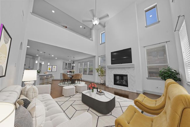 Living room featuring light wood-style flooring, recessed lighting, a premium fireplace, a high ceiling, and ceiling fan | Image 5