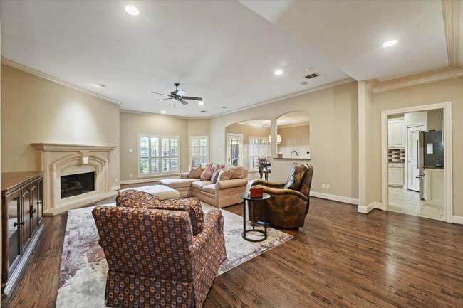 Living room with arched walkways, ornamental molding, ceiling fan, dark wood-type flooring, and a premium fireplace | Image 9