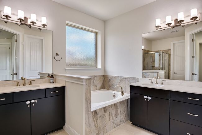 Full bathroom featuring a stall shower, two vanities, a bath, and tile patterned flooring | Image 23