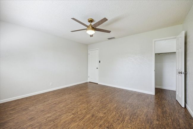 Unfurnished bedroom with dark wood-style flooring, a textured ceiling, ceiling fan, and a walk in closet | Image 25