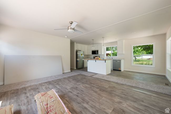 Unfurnished living room featuring ceiling fan, wood finished floors, and baseboards | Image 6