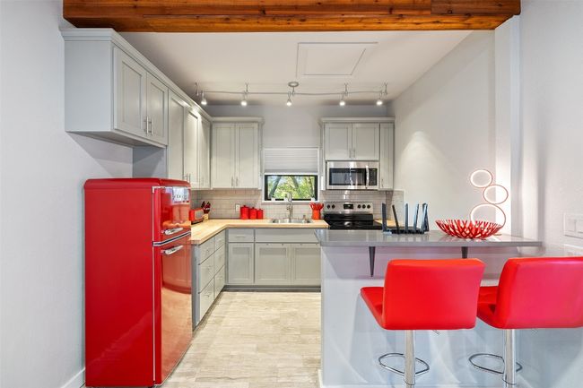 Kitchen featuring stainless steel appliances, tasteful backsplash, a breakfast bar area, a peninsula, and light countertops | Image 38