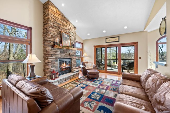 Fabulous scenic views combined with a floor to ceiling stacked stone gas fireplace make this breathtaking space the perfect living room. | Image 7