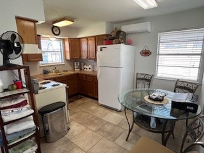 Guest house Kitchen featuring freestanding refrigerator, a wall mounted air conditioner, brown cabinetry, and extractor fan | Image 19