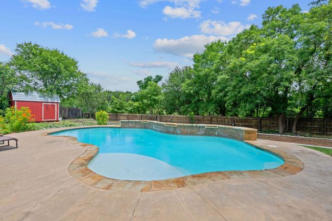 View of pool with a fenced backyard, a storage shed, a patio, and view of wooded area | Image 5