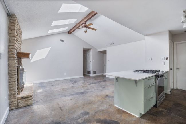 Kitchen featuring green cabinetry, a skylight, stainless steel gas range oven, concrete floors, and light countertops | Image 9