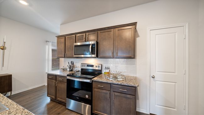Kitchen with appliances with stainless steel finishes, light stone countertops, tasteful backsplash, dark wood-style flooring, and dark brown cabinetry | Image 8