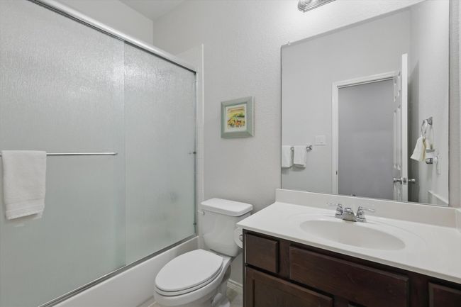 Full bathroom featuring shower / bath combination with glass door, toilet, and vanity | Image 5