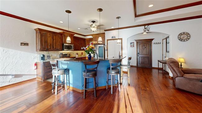 Kitchen featuring a kitchen breakfast bar, arched walkways, backsplash, a ceiling fan, and appliances with stainless steel finishes | Image 19
