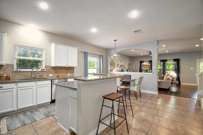 A large kitchen illuminated with natural light and recessed light fixtures. | Image 10