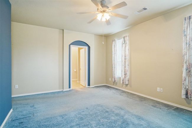 Primary Bedroom featuring baseboards, visible vents, arched walkways, ceiling fan, and carpet | Image 16