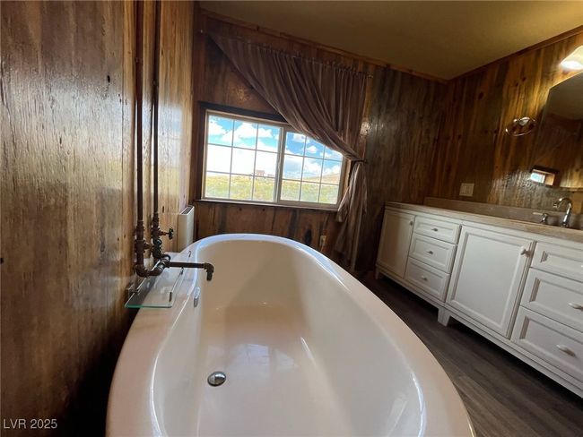 Full bath featuring vanity, wood walls, and a freestanding bath | Image 10