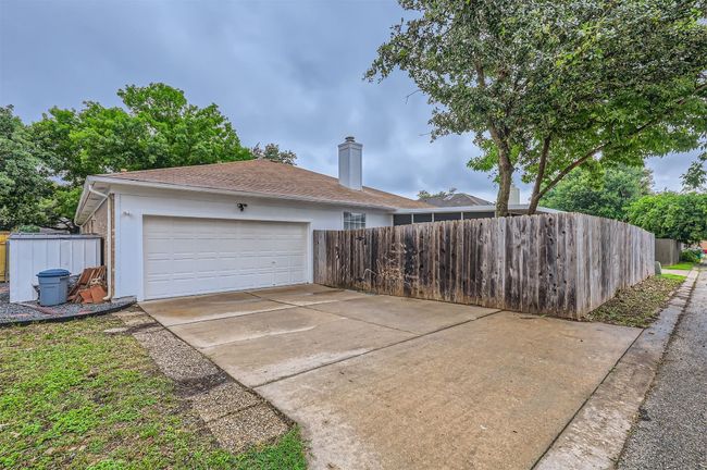 View of side of property featuring a chimney, stucco siding, driveway, and a shingled roof | Image 28