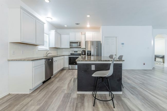 Kitchen featuring a center island, arched walkways, a sink, light wood finished floors, and stainless steel appliances | Image 5