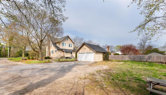 View of side of home featuring an outdoor structure, stone siding, a garage, and fence | Image 16