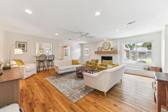 Relax in the spacious family room with elegant wood floors, a cozy brick fireplace, large windows, and seamless access to the back patio. | Image 5