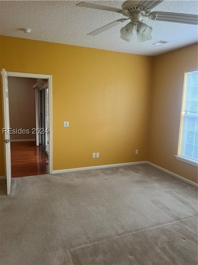 Carpeted empty room with ceiling fan and a textured ceiling | Image 16